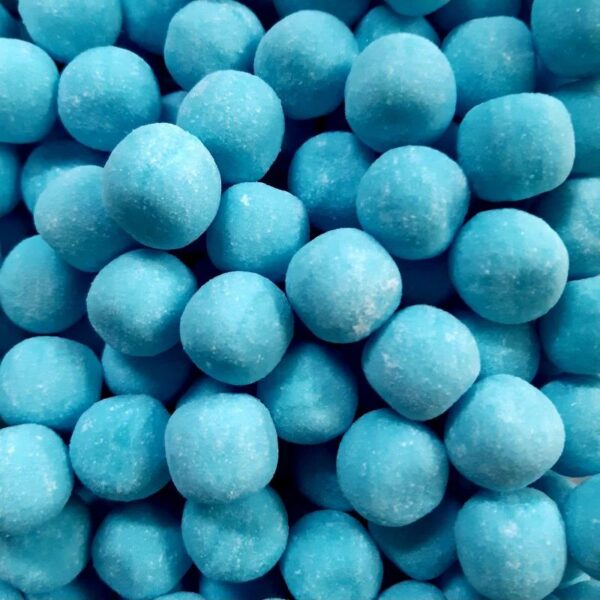 Gros plan sur des bonbons durs en forme de boules bleues saupoudrées de sucre acidulé, saveur mûre sauvage.