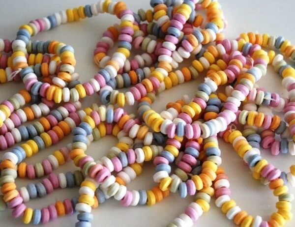 Amas de colliers de bonbons vintage constitués de petites pastilles de dextrose multicolores (pastel) enfilées sur un fil élastique blanc.