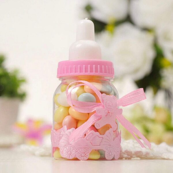 Mini biberon de baptême rose transparent rempli de bonbons colorés avec ruban et ourson décoratif.