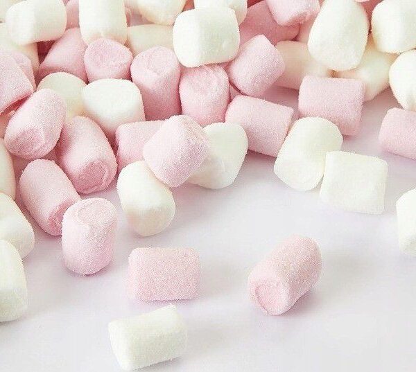 Mélange de mini guimauves cylindriques Haribo, couleurs rose pastel et blanc, texture moelleuse pour décoration de dessert.