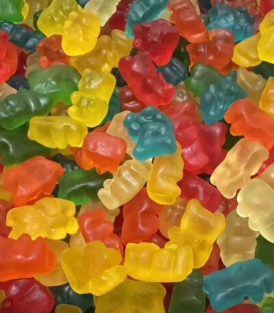 Multitude de petits oursons gélifiés multicolores (rouge, jaune, vert, orange, bleu, blanc) avec une texture brillante, certifiés Halal.